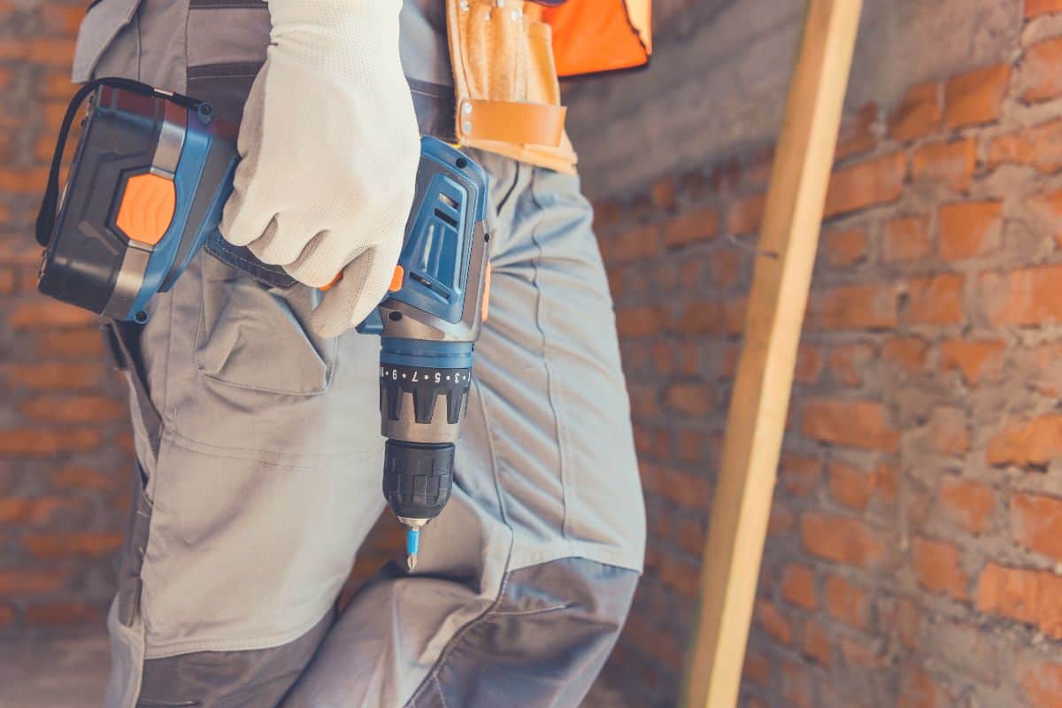 A person holding a cordless hammer drill on a job site