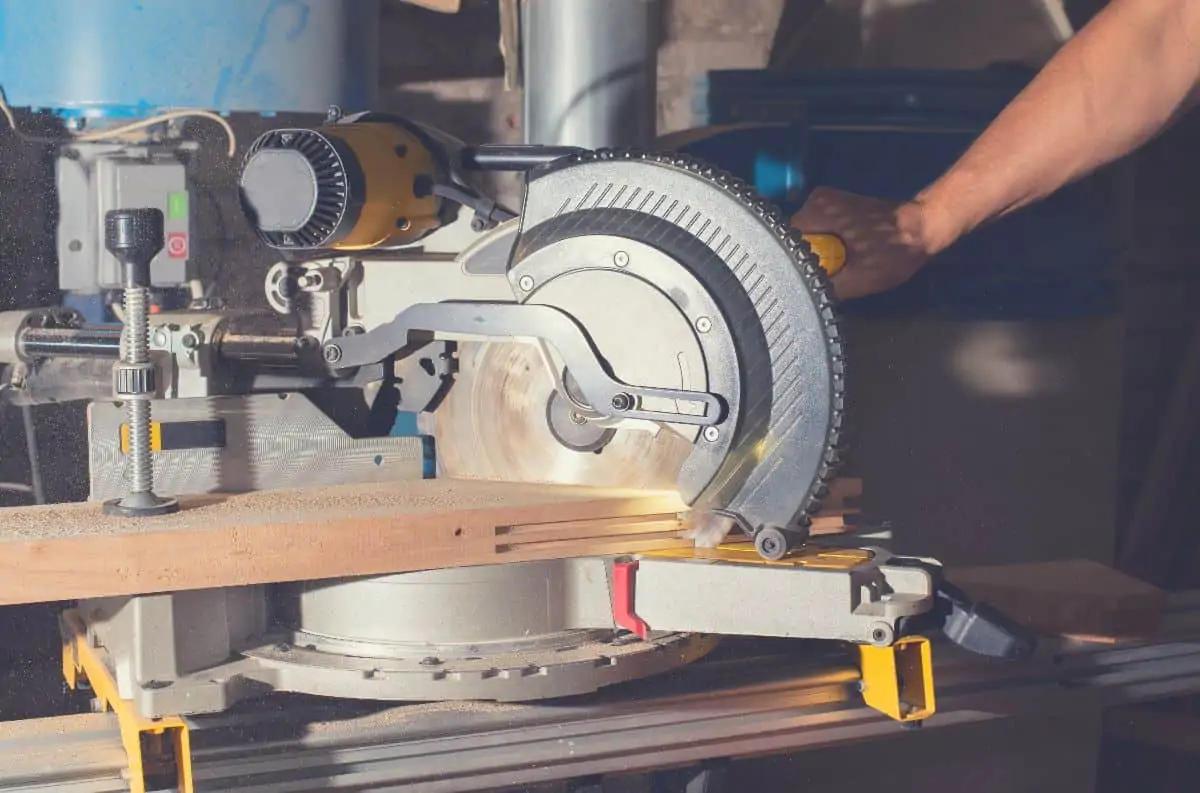 Close up of someone using a miter saw mounted on a stand