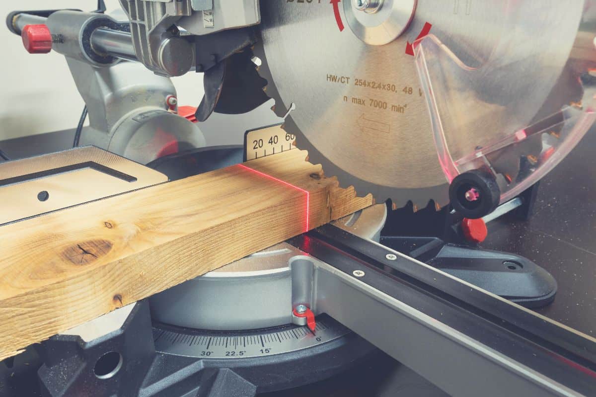 A miter saw blade set up to make a cut in a piece of wood