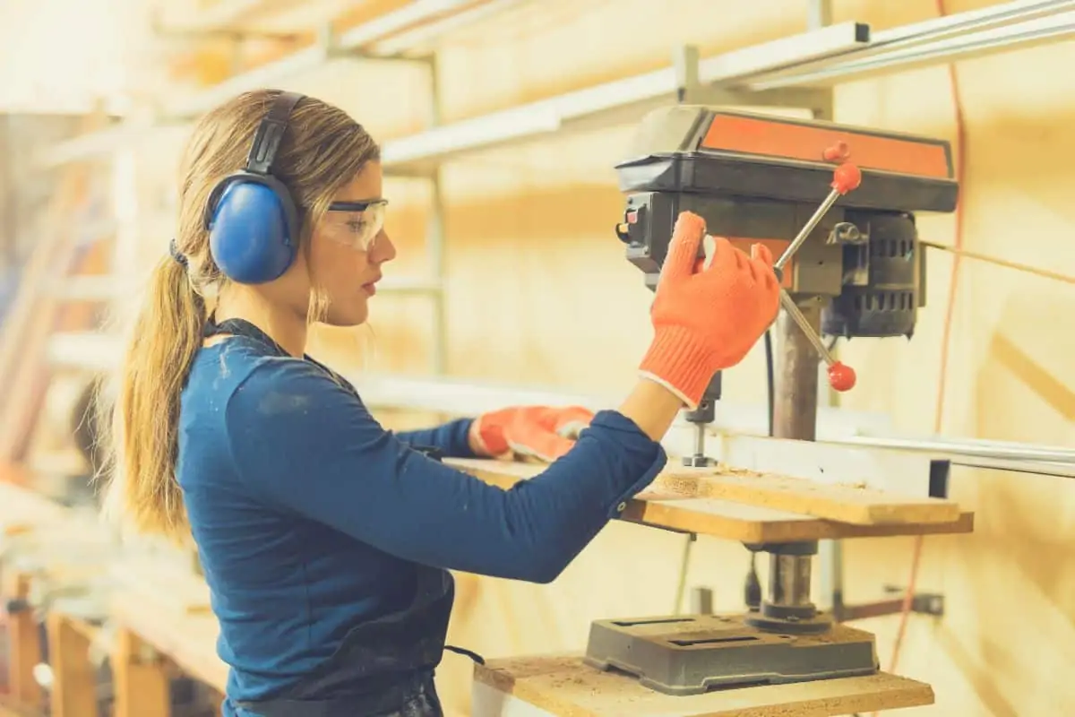 A female carpenter using a dress press to drill holes in wood