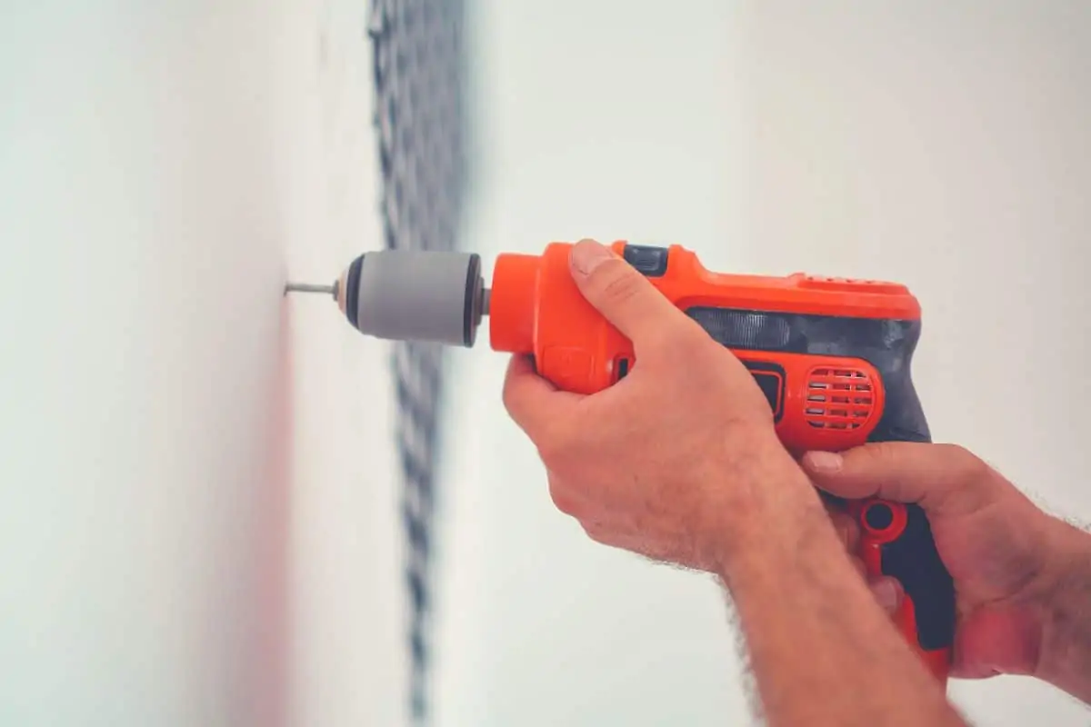 Someone drill a hole in a wall with a corded drill