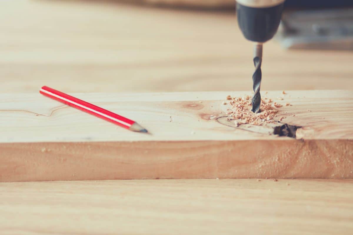 A Carpenter drilling into a piece of wood with a drill