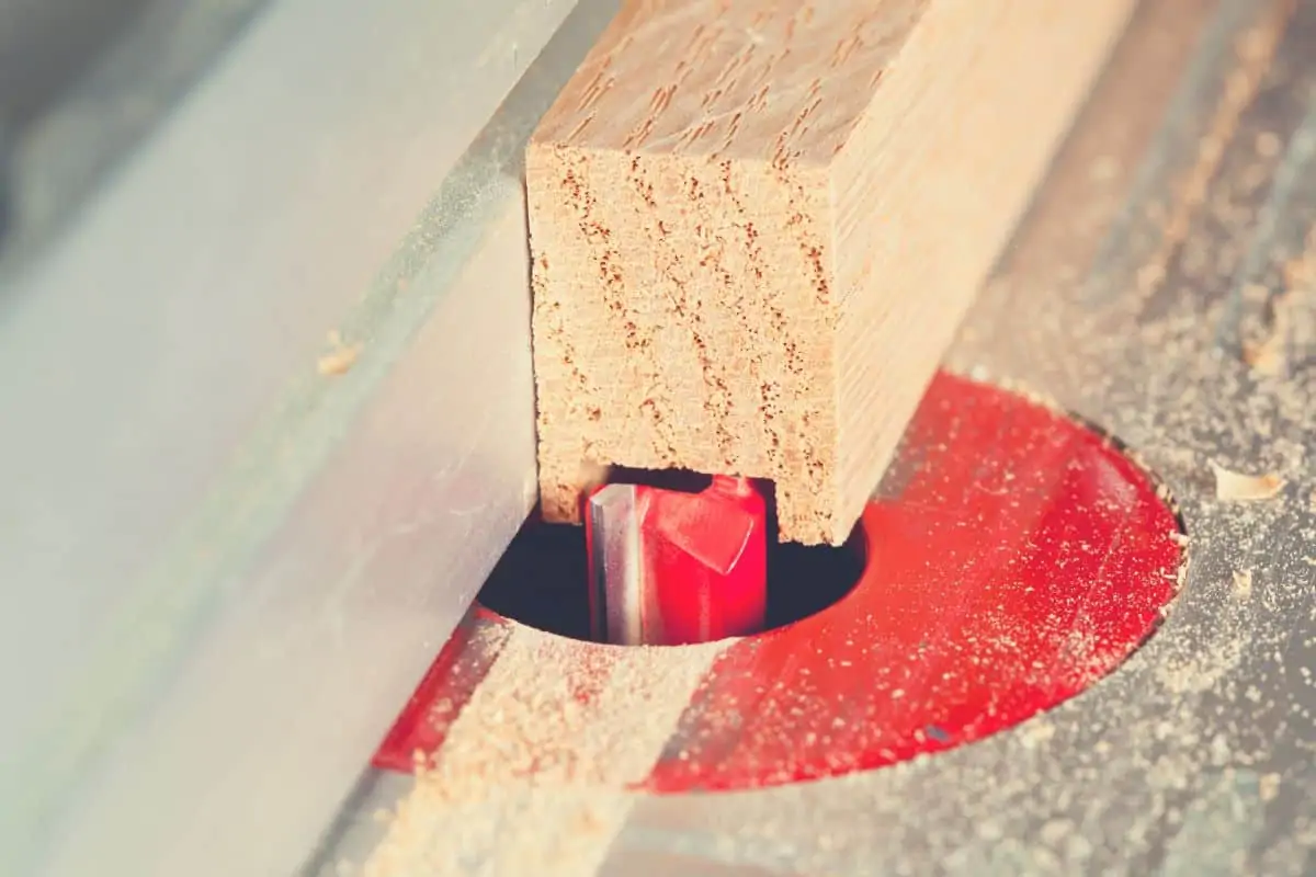A close up of a router bit cutting wood on a router table