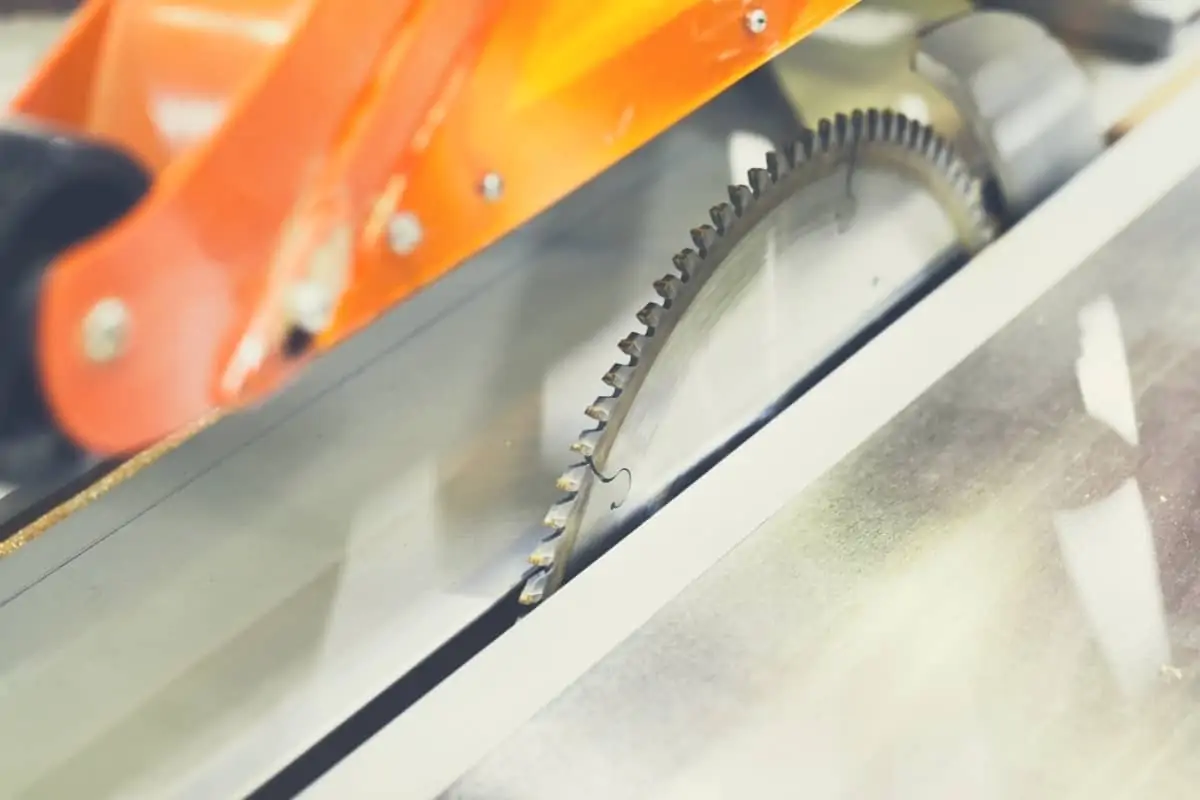 A close up image of a table saw blade with a guard and riveting knife.