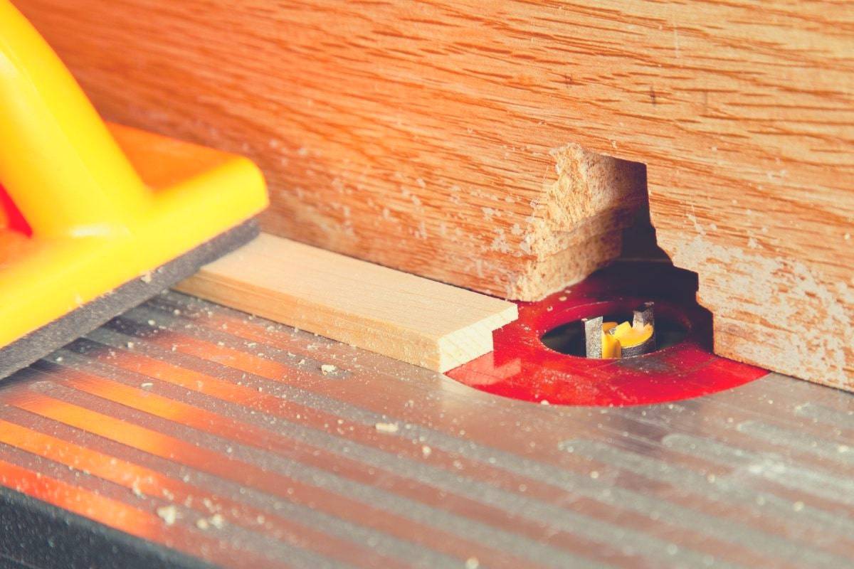 A close up image of a workpiece being fed through a router bit on a router table