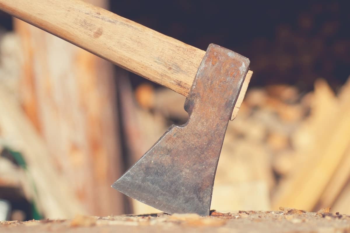An axe stuck into a piece of wood. 
