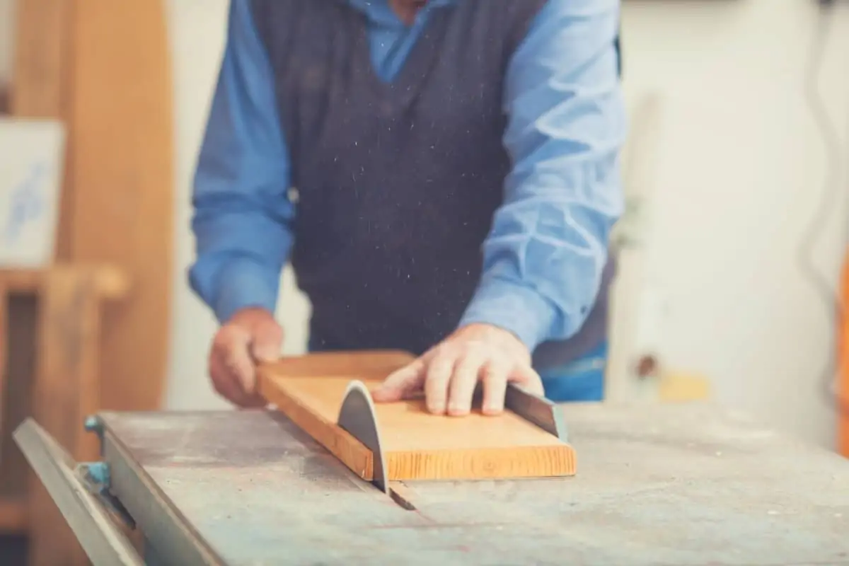 A man ripping a wooden board using a table saw