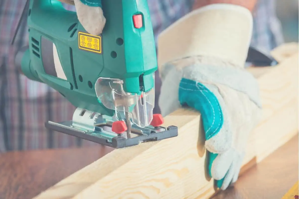 A close up of a woodworker cutting a piece of wood with a jigsaw