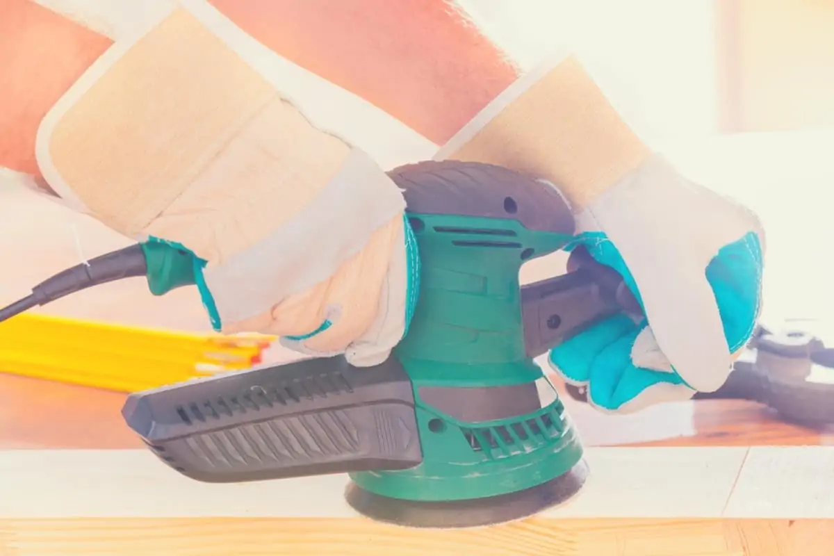 A man using an orbital sander to finish a piece of wood