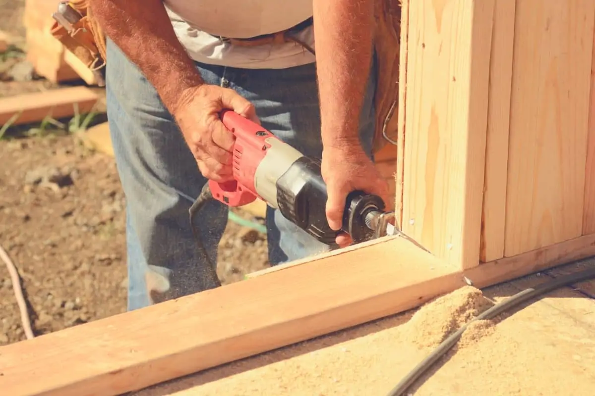 A man cutting some timber framing with a reciprocating saw